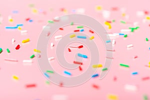 colorful sprinkles over pink background, decoration