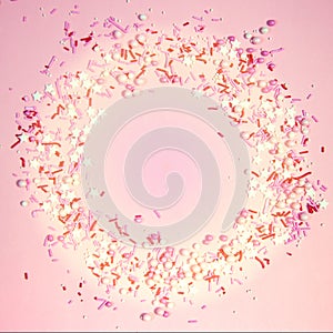 Colorful sprinkles on a pink background, top view with copy space