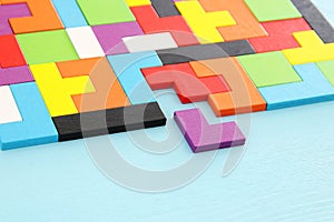 A colorful square tangram puzzle, over wooden table.