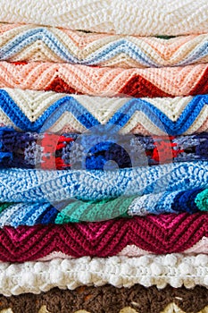 A colorful stack of folded crochet afghans