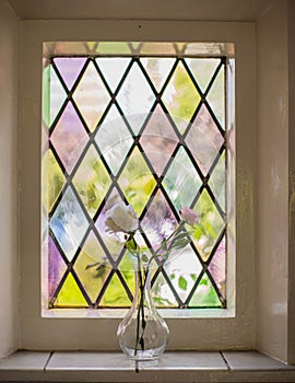 Colorful stained glass with flowers in vase in the light