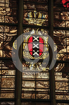 Colorful stained glass window inside the gothic old church with the coat of arms of Amsterdam.