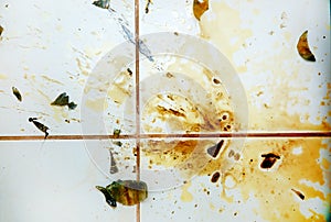 Colorful stains and broken glass on white bathroom tiles.