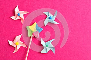 A colorful star shape lollipop with colorful pinwheels on a pink background