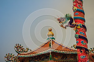 Colorful statue of Chinese dragon wrapped around red pillar. Beautiful statue of dragon carved around temple pole in Chinese