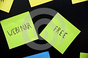 Colorful sticky notes on black board reminder. Free webinar written sticker on pineboard. Register for free online webinar