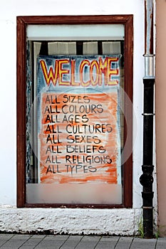 Colorful store window welcome sign to people of all types religions beliefs sexes cultures ages colours and sizes