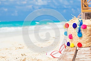 Colorful straw bag, sunglasses and flip flops on a tropical caribbean beach