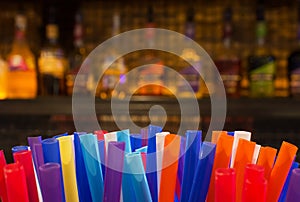 Colorful Straws and Blurred Bottles of Spirits and Liquor in the Bar