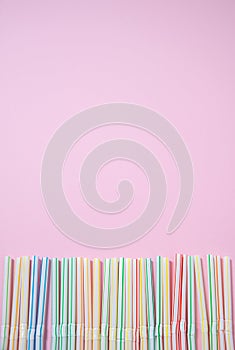 Colorful straws for a cocktail on a pink background.