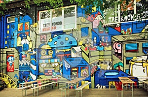 Colorful street art by unknown artist on wall of popular outdoor cafe of Berlin