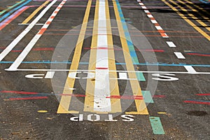 Colorful street line testing site with multiple lines in various colors and shapes with letters painted on paved surface