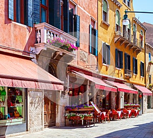 Colorful street with tables of cafe at a sunny morning, Venice, Italy