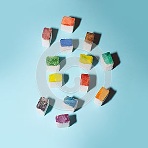 Colorful sugar cubes form a crowd on a blue background. People metaphor. Creative food concept