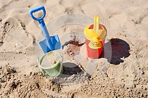 Colorful summer beach toys, bucket, sprinkler and shovel on sand