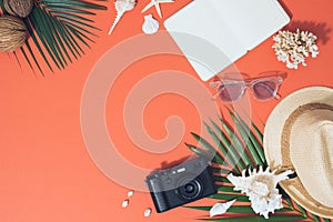 Colorful summer holidays fashion flat lay - straw hat, camera, sunglasses, sea shells on bright orange background