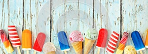 Colorful summer popsicles and ice cream treats bottom border on a rustic blue wood banner background