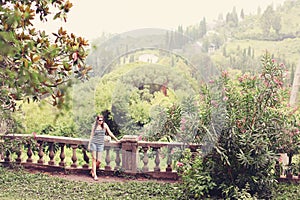 Colorful summer tree with woman standing and contemplating nature. Young girl in a sunglasses walking alone in a forest