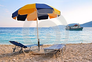 Colorful sun umbrella and two sunbeds on a beach