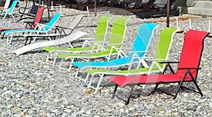 Colorful sunbeds on a deserted pebble beach