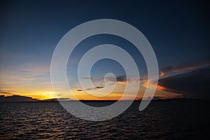 Colorful sunrise with blue sky, orange clouds and rippled sea. Orange blue skyscape in early morning