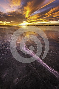 Colorful Sunrise on the Frozen Lake with ice cracks glowing