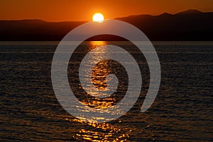 Colorful sunrise landscape. Big sun on orange sky over silhouette of mountains. Lake Liptovska Mara, Slovakia