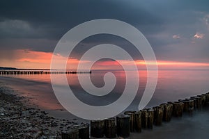 Colorful sunset at a beach of the baltic sea with groins in the forground