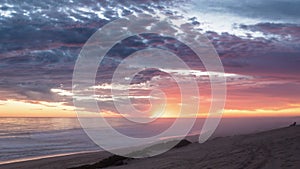 Colorful sunset with bloody sky and red clouds over ocean coast beach in summer evening Time lapse