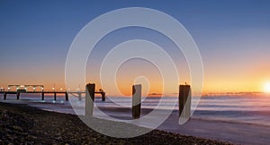 Colorful  sunset on a calm sea with pier at the background