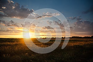 Colorful sunset on a cloudy sky background in a field, summer na