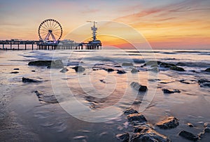 Colorful sunset on coastline, beach, pier and ferries wheel, Scheveningen, the Hague