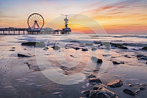 Colorful sunset on coastline, beach, pier and ferris wheel,