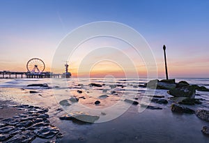 Colorful sunset on coastline, beach, pier and ferris wheel, Scheveningen, the Hague