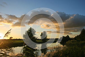 Colorful sunset with cumulus clouds over a small lake near Gouda, The Netherlands