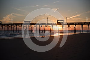 Colorful Sunset at ocean coast with silhouette of pier and photo