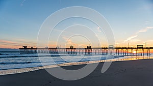 Colorful Sunset at ocean coast with silhouette of pier and photo