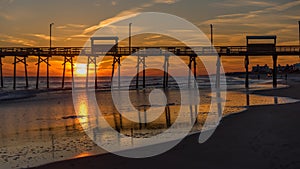 Colorful Sunset at ocean coast with silhouette of pier and photo