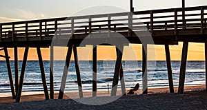 Colorful Sunset at ocean coast with silhouette of pier and photo