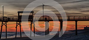 Colorful Sunset at ocean coast with silhouette of pier and photo