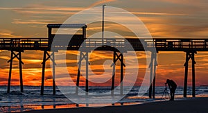 Colorful Sunset at ocean coast with silhouette of pier and photo