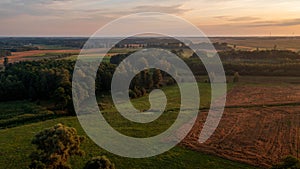 Colorful sunset over forest and fields aerial