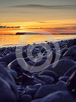 Colorful sunset over ocean, rough stone coast in foreground. Warm and cool color. Salthill beach, Galway city, Ireland. Selective