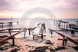 Colorful sunset over the sea shore. Old rusty boat berths. Long exposure smooth water waves effect