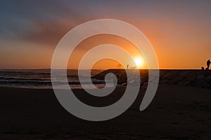 Colorful sunset with silhouettes in contrast in breakwater with sea drops on Vieira beach, Marinha Grande PORTUGAL