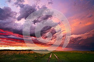 Colorful sunset sky over a dirt road and field