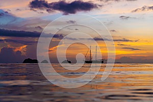 Colorful sunset on a tropical beach. Orange sunset on the ocean. Colorful sunset in the tropics. In the water is a sailing ship.