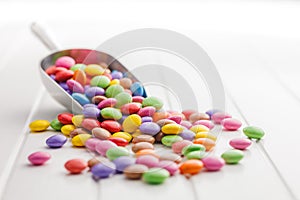 Colorful sweet candies in scoop on white table