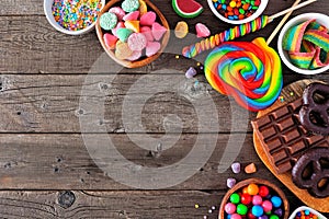 Colorful sweet candy buffet corner border, top view table scene over a rustic wood background