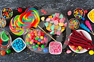 Colorful sweet candy buffet table scene, above view over dark stone